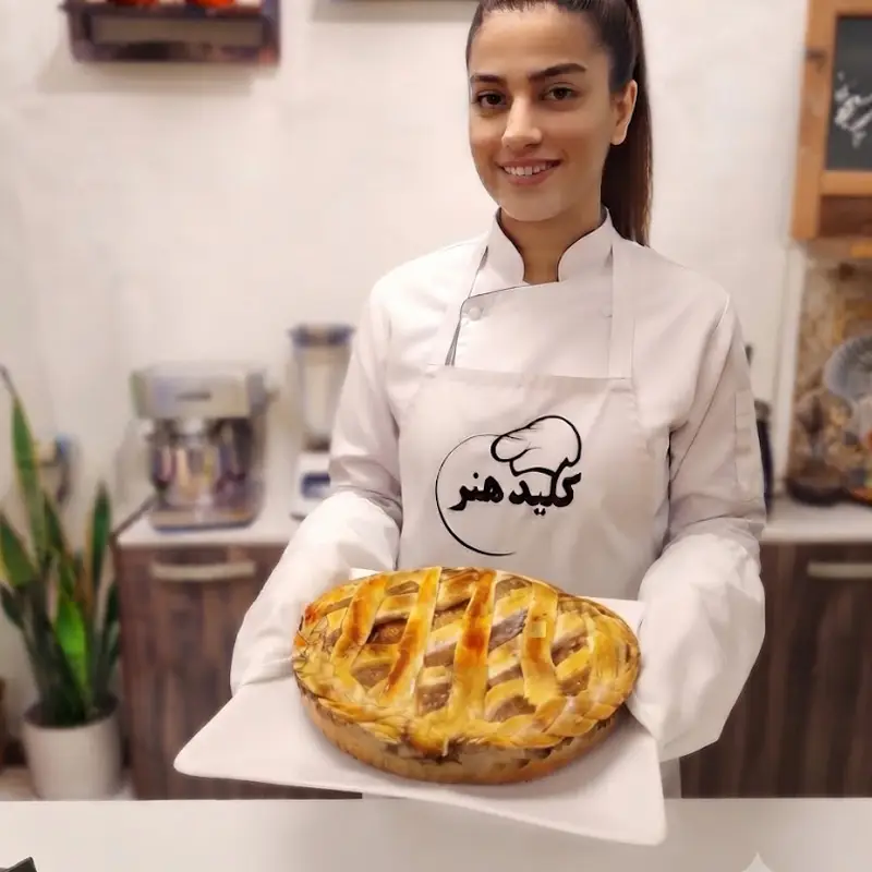 هنرجوی دوره آشپزی ایتالیایی کلید هنر در حال ارائه پای ایتالیایی با خمیر شبکه‌ای طلایی (کروستاتا)